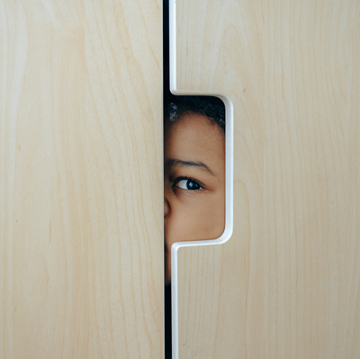 Child peeking from behind a door